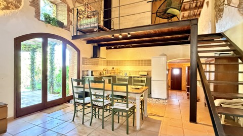 Dining area with arched garden door and mezzanine above – Mas Santa Caterina